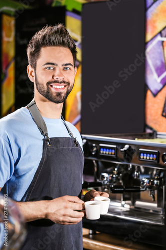 Young barista with cups of hot coffee in cafe © Pixel-Shot