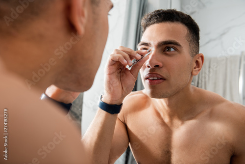 Close up of man plucking eyebrow hairs