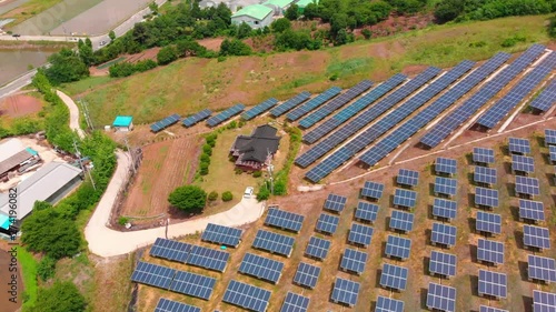 Aerial zenith tilt down above solar power plant and traditional asian style house photo