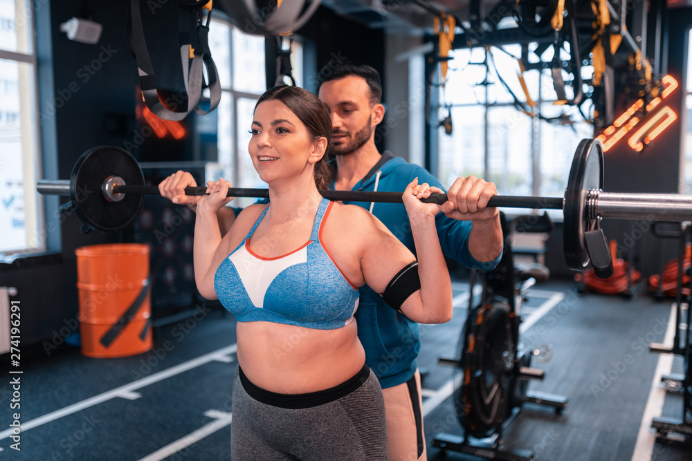 © Viacheslav Yakobchuk - Plump woman working out with barbell near trainer