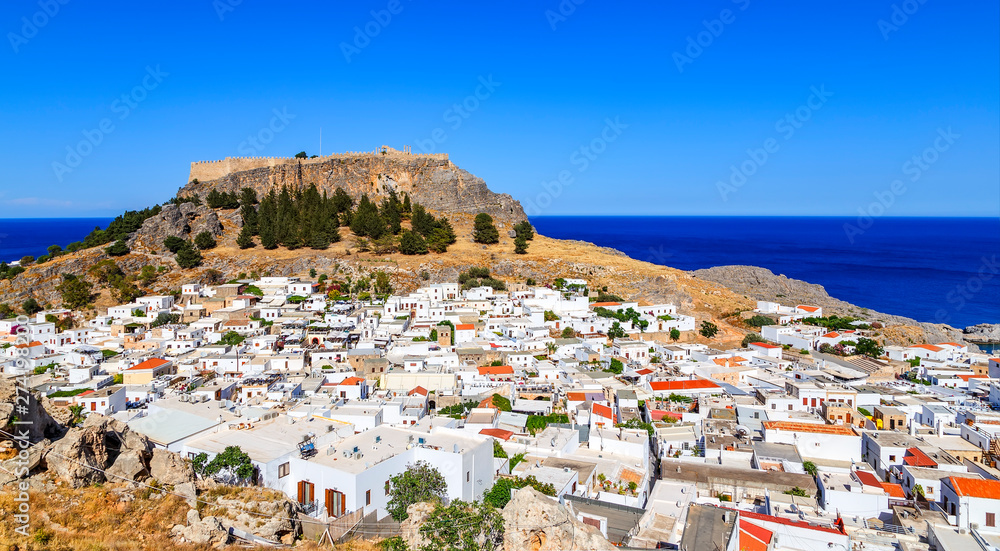 Small whitewashed village of Lindos with Acropolis at foot of mountain. Scenery of Rhodes island at Aegean sea.