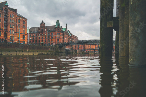 low angle view of channel and historic warehouses in the Speicherstadt district of Hamburg against clouded sky
