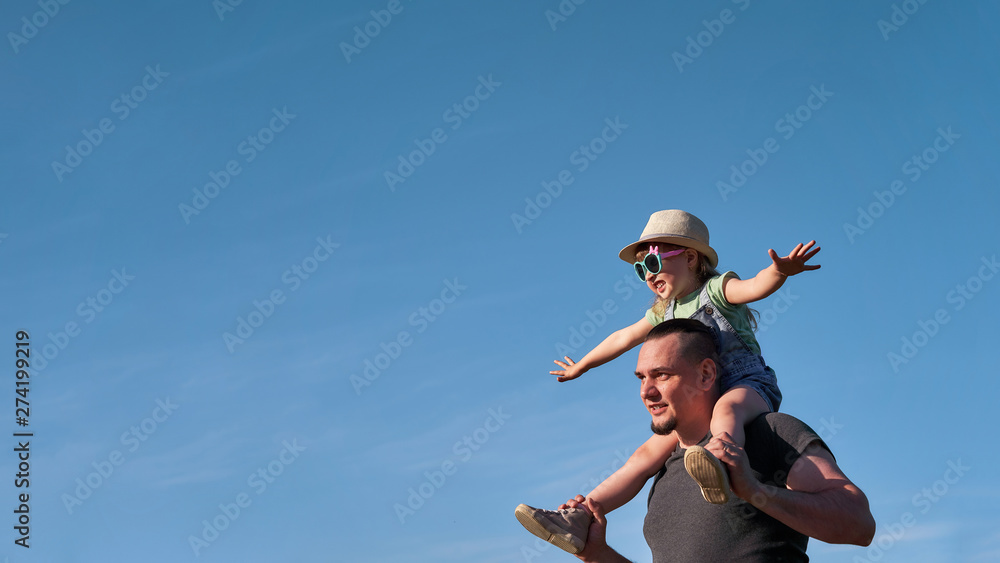 father and daughter on shoulders happily rejoice. dad holding little daughter sitting on mimics the flight of the Pope father and daughter on shoulders happily rejoice. dad holding little daughter sitting on mimics the flight of the Pope