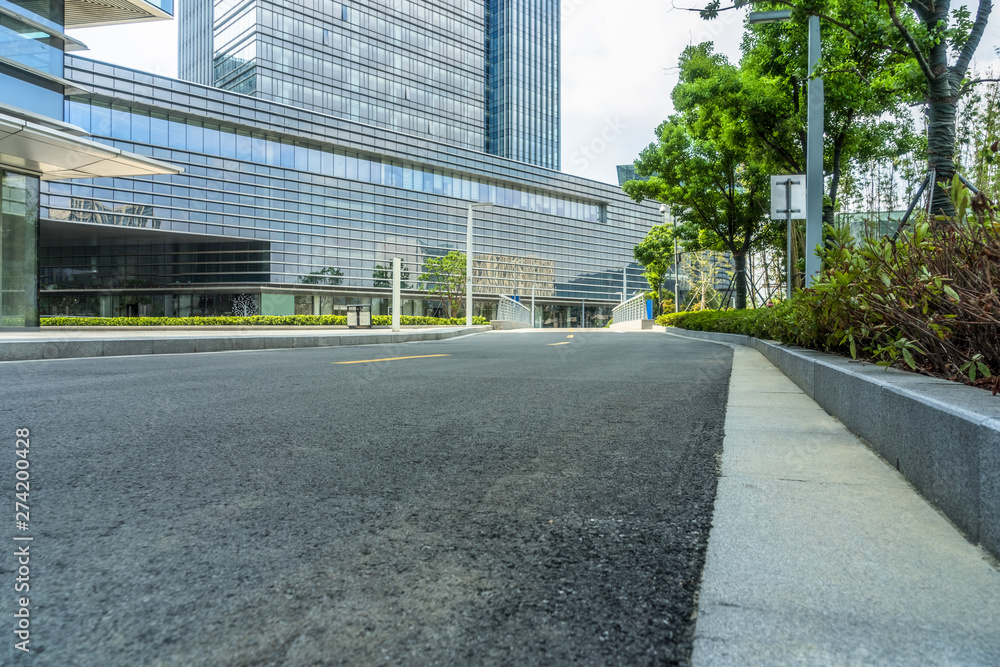 empty asphalt road near glass office building.