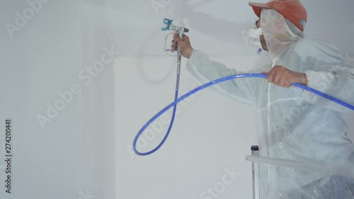 beauty slow motion. repair of the apartment - professional painter paints the walls with white paint spray gun