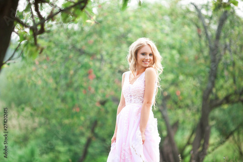 beautiful young woman in a gentle pink dress on nature
