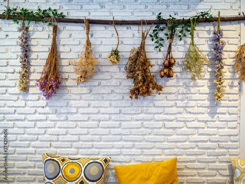 Various vintage colorful dried flowers hanging on white brick wall