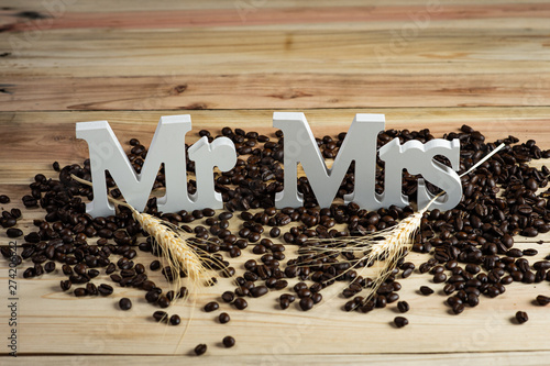 Mr and Mrs word text wedding sign with dry flowers and brown roasted coffee beans on bright wooden background. photo