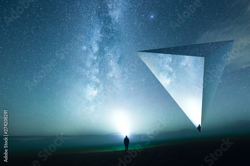 Eine Person mit Kopflampe leuchtet die Sterne an, surreale Landschaft mit Tetraeder
