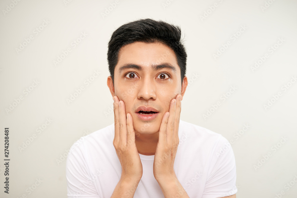 Handsome Asian man is touching his face and smiling while looking into the mirror Handsome Asian man is touching his face and smiling while looking into the mirror