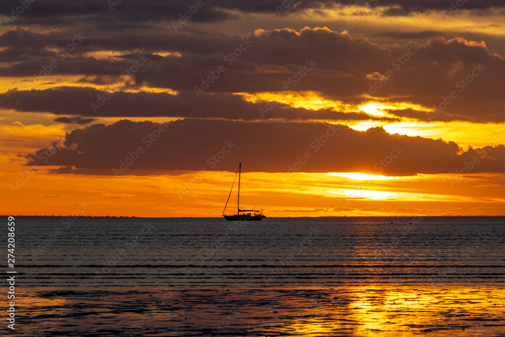 Yacht sailing into golden sunset 