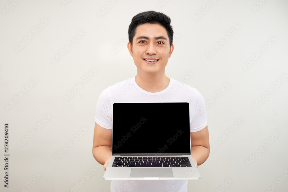 Smiling young asian man dressed in shirt showing blank screen laptop computer over white background Smiling young asian man dressed in shirt showing blank screen laptop computer over white background
