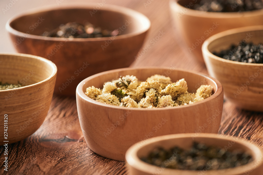 assortment of dry tea in white bowls on wooden surface assortment of dry tea in white bowls on wooden surface
