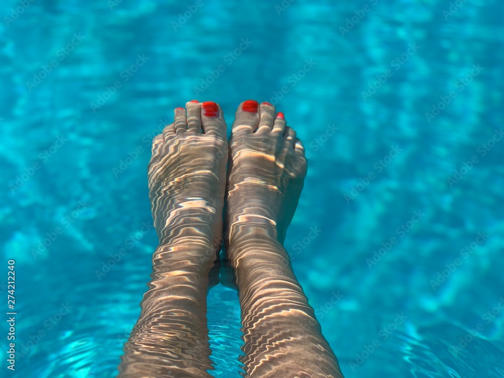 female feet in the sweeming pool 
