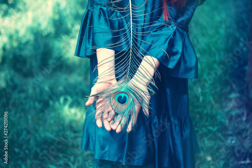 Peacock feather in woman's hand