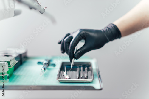 Hand of a dentist picking dental tool.