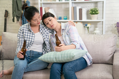 Young sad girl talking with her best friend about problems. upset asian woman leaning on sisters shoulder holding beer drinking alcohol to make self better. lady hug consoling for help and support