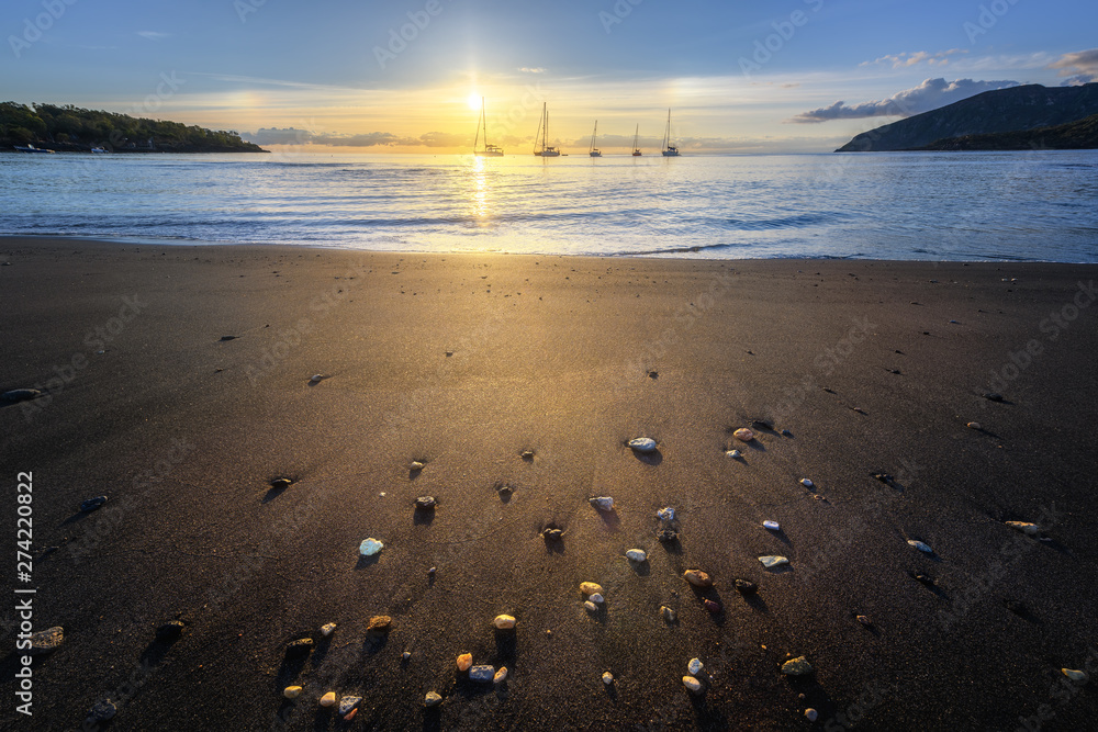 Obraz premium Wide angle lens shot of black sand beach at sunset with boats in the far side, Vulcano Island, Eolian Islands, Sicily, Italy