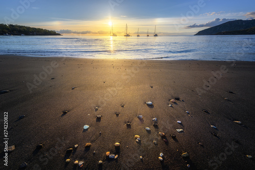 Fototapeta Naklejka Na Ścianę i Meble -  Wide angle lens shot of black sand beach at sunset with boats in the far side, Vulcano Island, Eolian Islands, Sicily, Italy