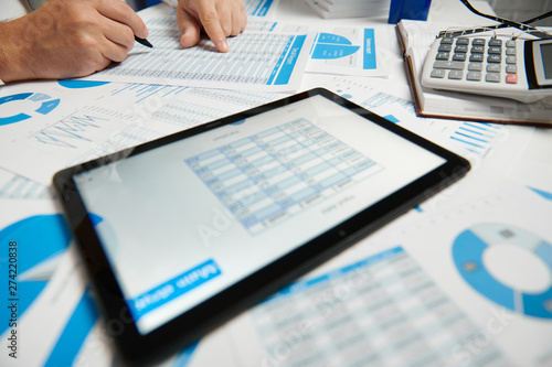 Businessman working and calculating, reads and writes reports. Using tablet pc. Office employee, table closeup. Business financial accounting concept.