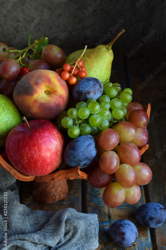 Autumn still life for thanksgiving with autumn fruits and berries on wooden background - grapes, apples, plums, viburnum, dogwood. Raw food. Copy space