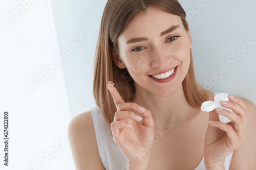 Fotografie Eye lens. Smiling woman with contact eye lenses and container