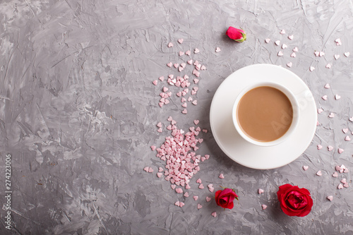 Red rose flowers and a cup of coffee on a gray concrete background. top view.