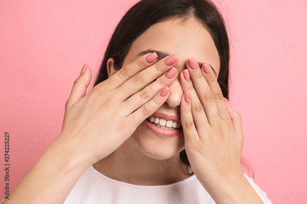 Portrait closeup of sweet joyful girl with long dark hair covering her eyes and peeking though hands Portrait closeup of sweet joyful girl with long dark hair covering her eyes and peeking though hands