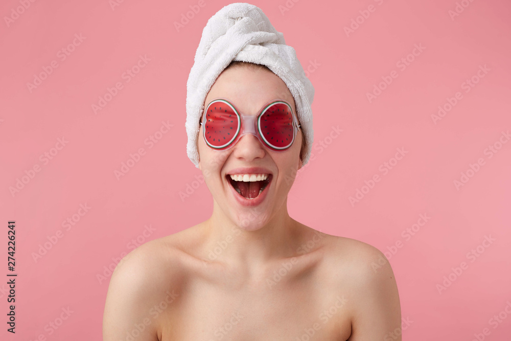 Wow! So cool! Young happy amazed woman after spa mask on eyes and with a towel on her head, with wide open mouth and eyes, hears cool news, stands over pink background. Wow! So cool! Young happy amazed woman after spa mask on eyes and with a towel on her head, with wide open mouth and eyes, hears cool news, stands over pink background.