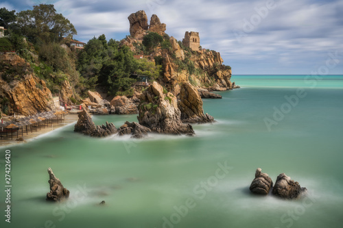 Rocks at cozy beach of Tyrrhenian sea. Long exposure shot of La Kalura bay, Cefalu, Sicily, Italy photo