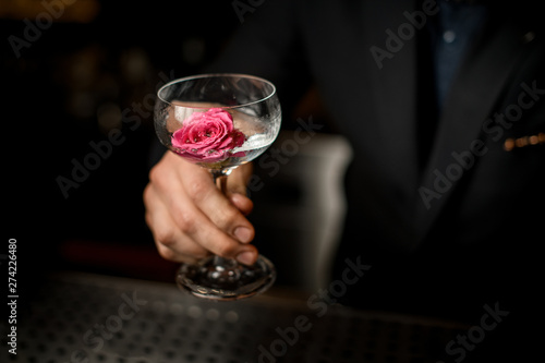 Close-up of bartender holding cocktail with flower