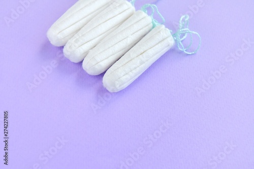 Cotton Hygienic tampons for women period days with selective focus on blurred purple background with empty space for text. Personal protection tampon for menstruated period. Females healthcare 