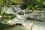 Langzeitbelichtung eines kaskadierten Wasserfalls umgeben von Bäumen im Dschungel.