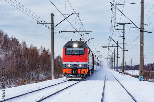 Passenger train approaches to the station at winter morning time.