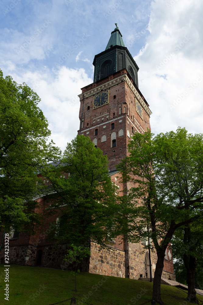 The tall tower of the historic medieval Gothic Cathedral of the 13th century and the park around Turku Abo on a summer day in Finland. Bottom view of the historic Lutheran Cathedral in Turku.