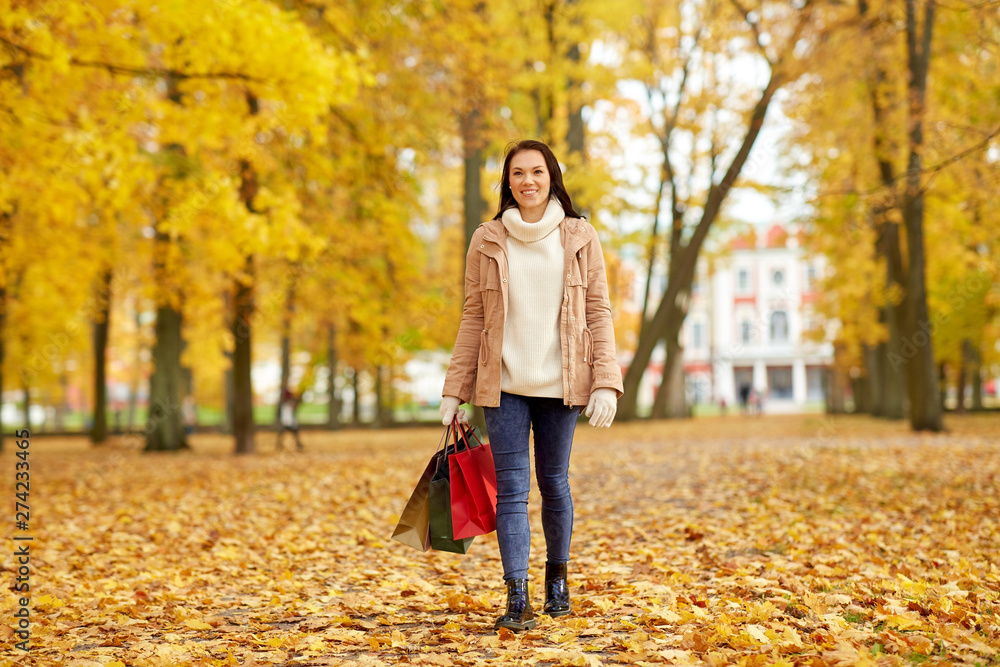 sale, consumerism, season and people concept - woman with shopping bags walking in autumn park sale, consumerism, season and people concept - woman with shopping bags walking in autumn park