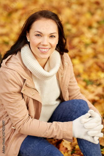 season and people concept - happy young woman smiling in autumn park