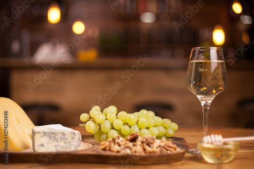 Photo of fresh grapes next to a wineglass on a wooden table