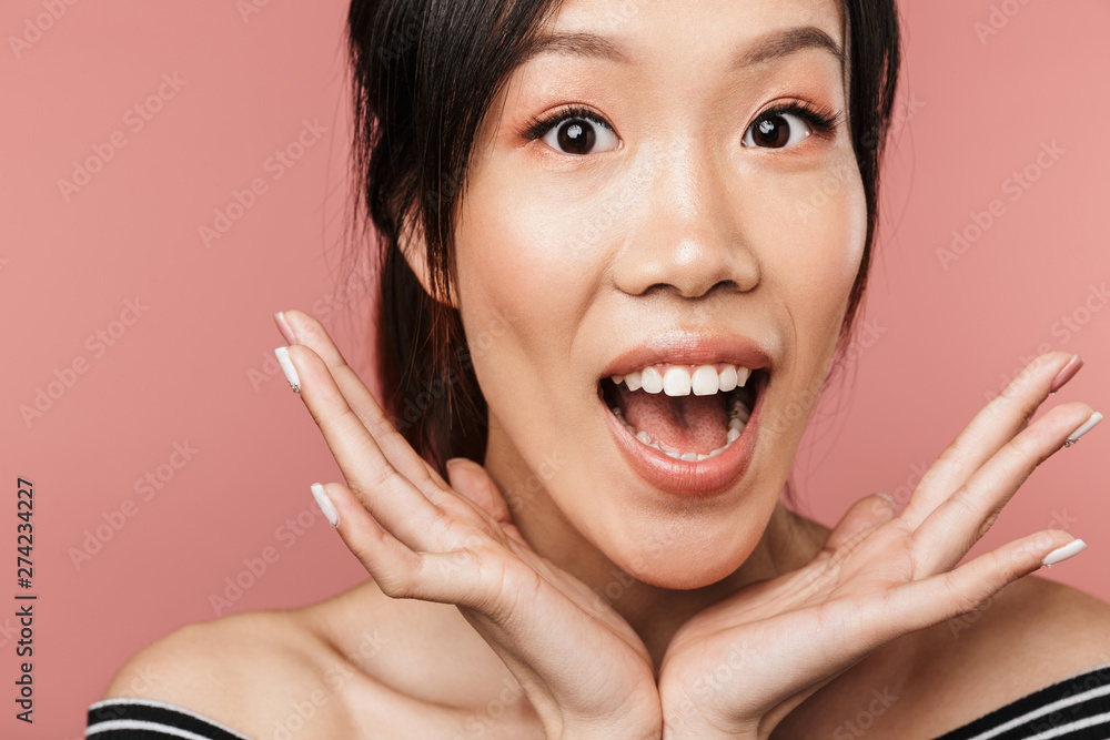 Photo of happy asian woman dressed in basic wear laughing and looking at camera Photo of happy asian woman dressed in basic wear laughing and looking at camera