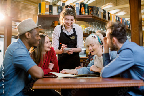 Waitress female welcoming diverse cafeteria pub guests making order waiting staff writing wishes on notepad. Good service dining time, friends meets in public place concept