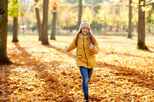 childhood  season and people concept - happy girl running in autumn park