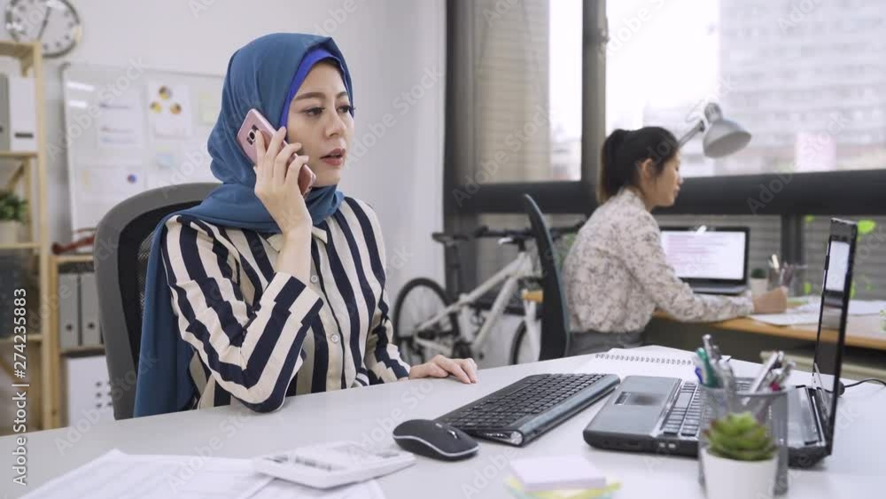 multi fashion designer group teamwork in modern office studio. young muslim boss talking on cellphone checking order with customer changing correcting mistake. chinese woman colleague listen writing multi fashion designer group teamwork in modern office studio. young muslim boss talking on cellphone checking order with customer changing correcting mistake. chinese woman colleague listen writing