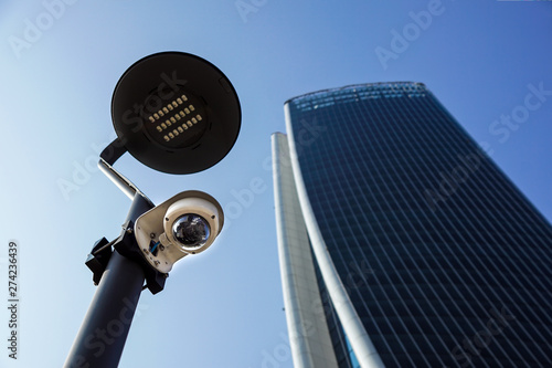 Camera system guarding blue skyscraper office building with sky above