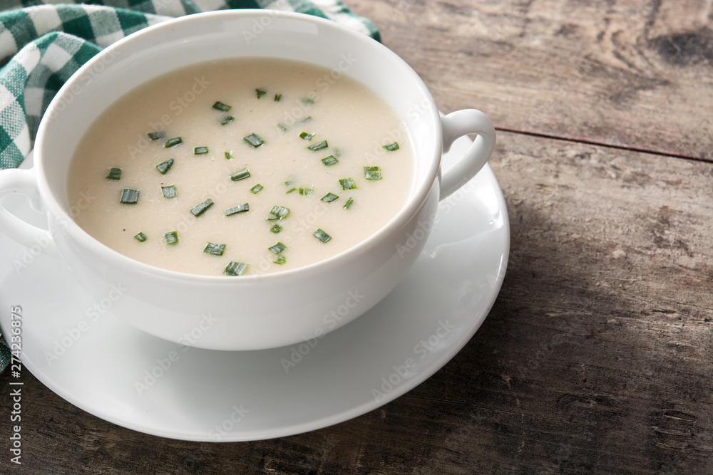 French vichyssoise soup in bowl on wooden table. Copyspace French vichyssoise soup in bowl on wooden table. Copyspace