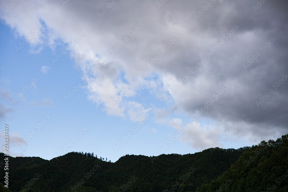 Dark rain clouds move in over clear blue sky in mountains