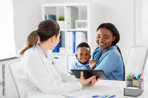 medicine, healthcare and pediatry concept - african american mother with baby son and caucasian doctor with tablet computer at clinic © Syda Productions