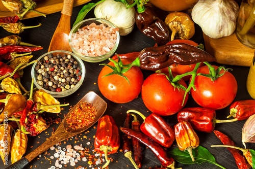 Fototapeta Naklejka Na Ścianę i Meble -  Homemade chili sauce. Spicy food. Chili peppers on black background. Bhutjolokia hot chilli pepper. Healthy food.