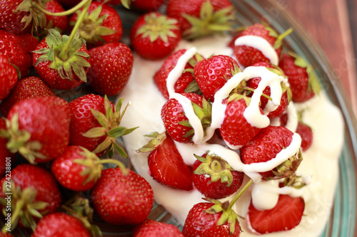 ripe  juicy strawberries with cream in a plate on a wooden table