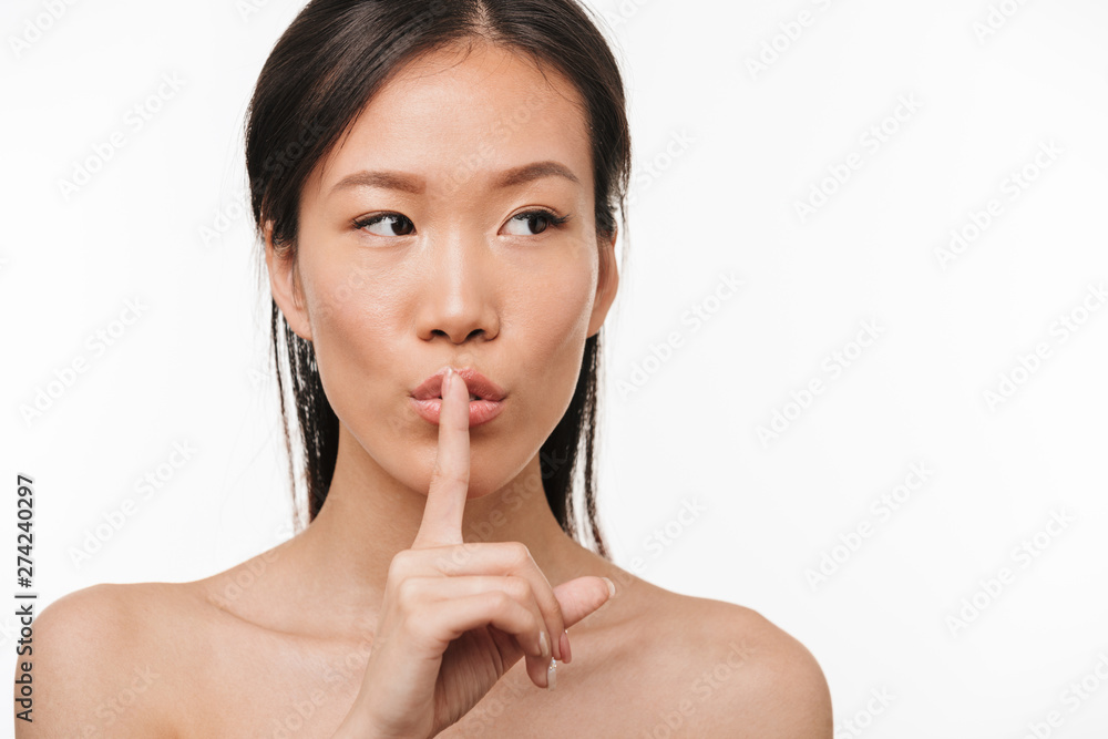 Serious young beautiful asian woman posing isolated over white wall background showing silence gesture. Serious young beautiful asian woman posing isolated over white wall background showing silence gesture.