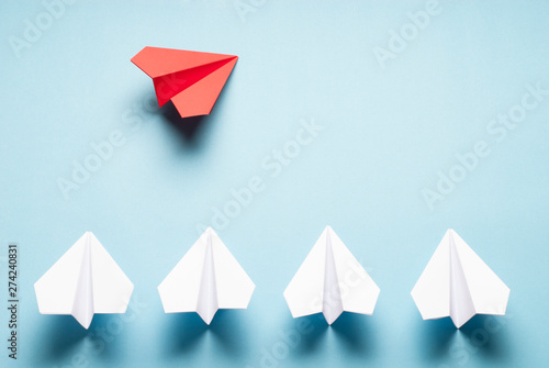 Red plane and white plane on blue background. Red and white origami planes. Minimalist composition with paper planes.